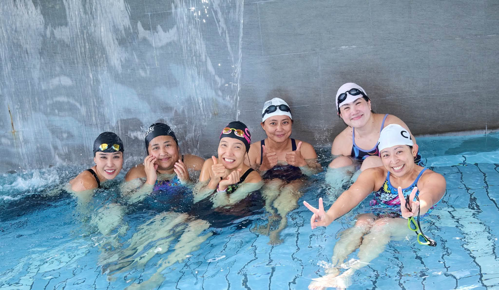 Smiling adult swimmers in caps together in the STAGE pool